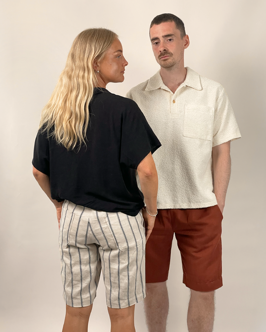 Two people standing side by side wearing casual clothing against a plain background
